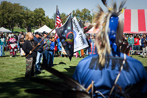 Several men hold Omaha Tribe flags on the Fort Omaha Fairgrounds