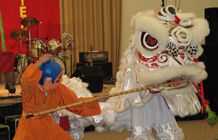 Two costumed people engaged in dragon and stick dance for Vietnamese New Year