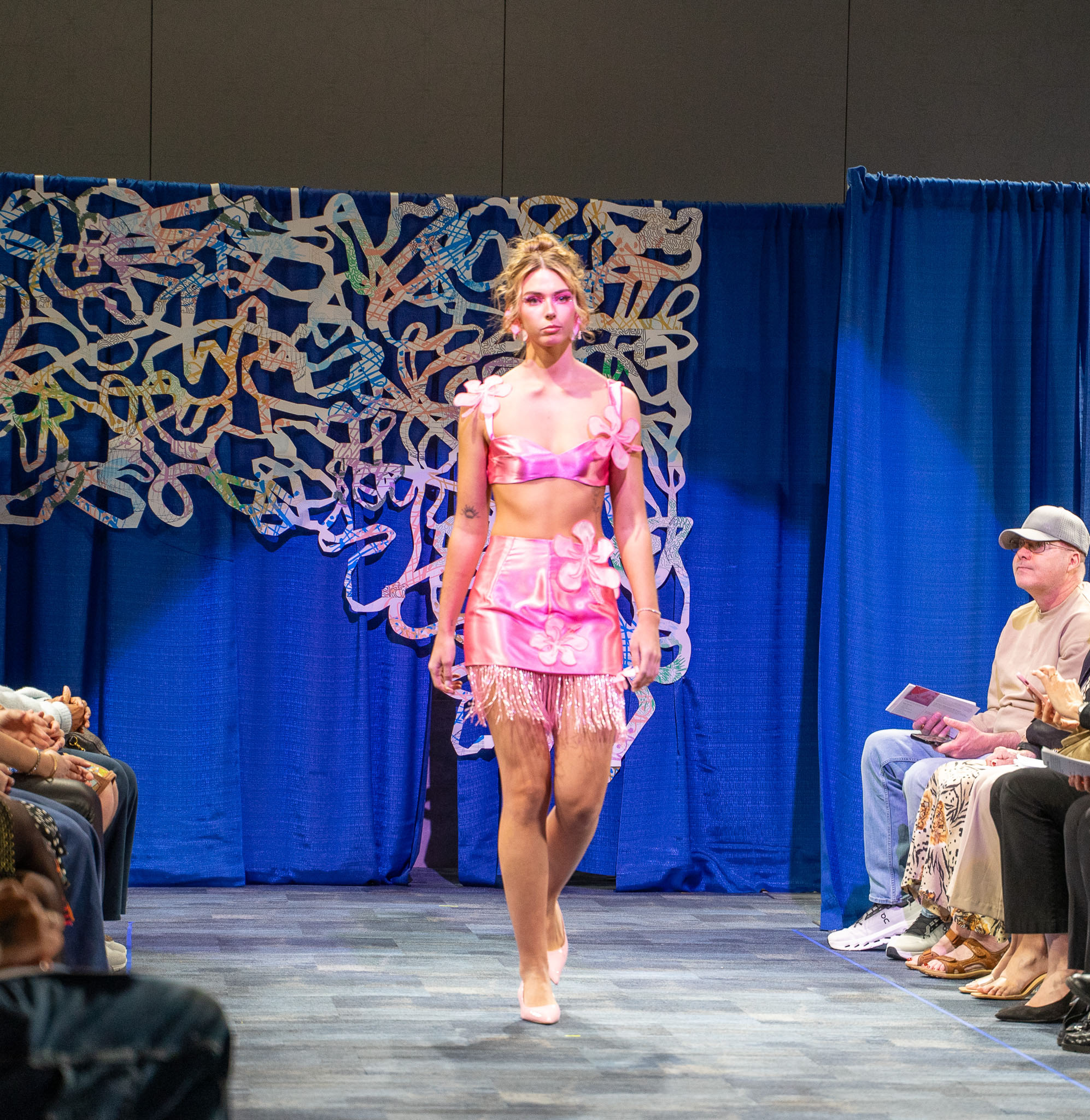 Student model in pink walking down runway