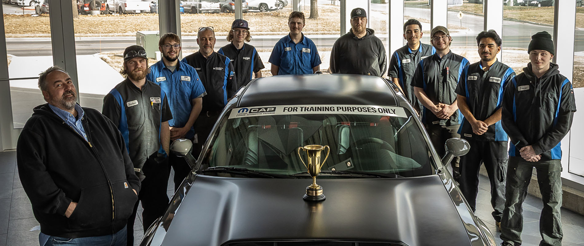 MCC Mopar CAP team posing with trophy placed atop car