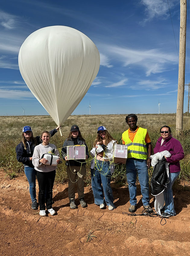 Students participating in research project posing with high-altitude that landed in a field