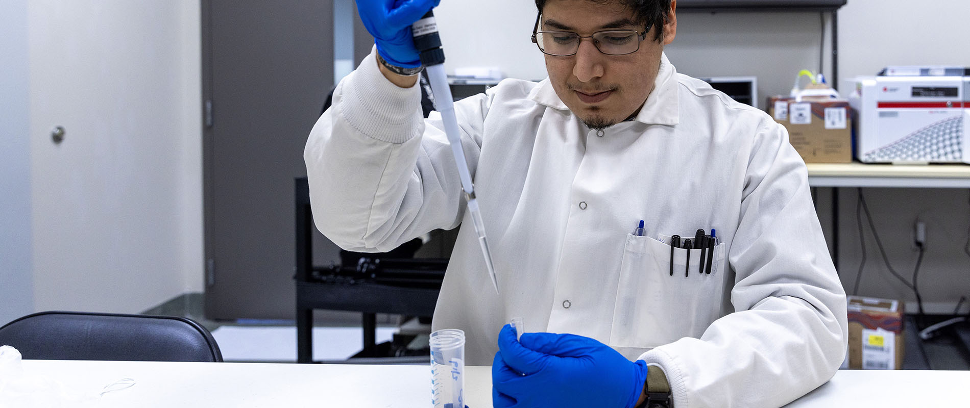 Student in a lab coat working lab equipment
