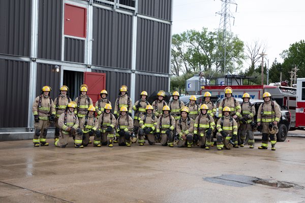 A group of firefighters stand outside the four story training tower