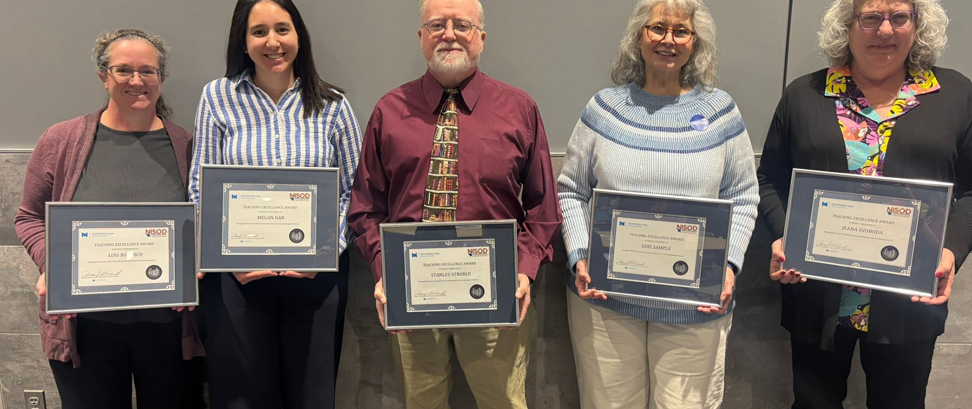 Group of people posing for picture with awards in their hands