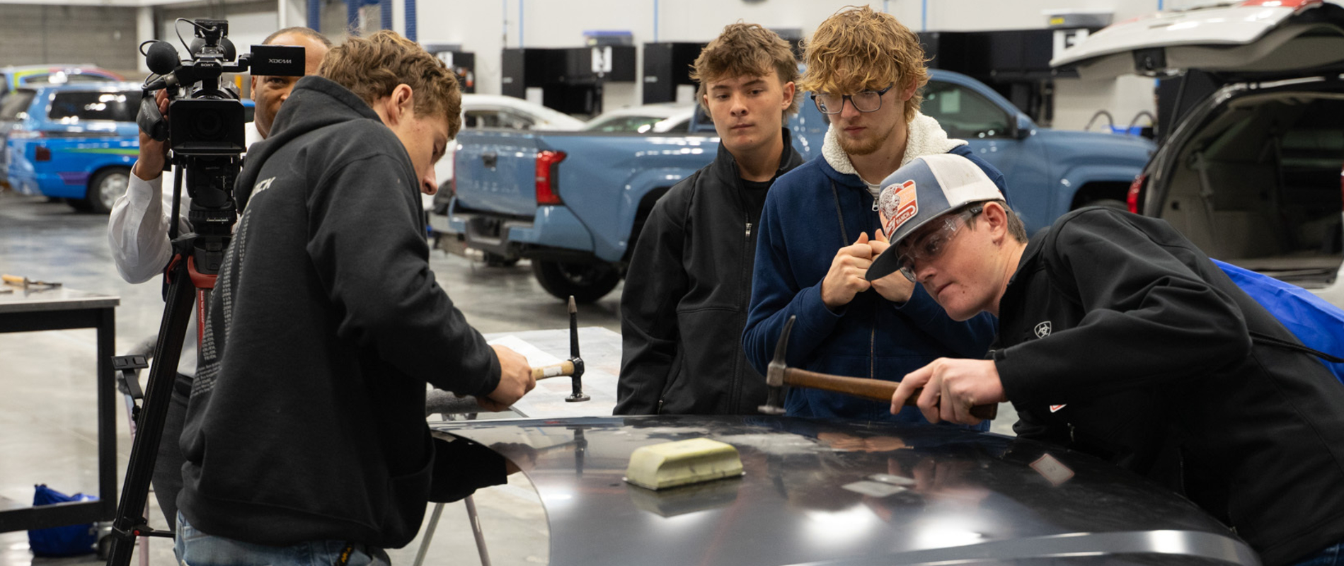 Students working on hood of car