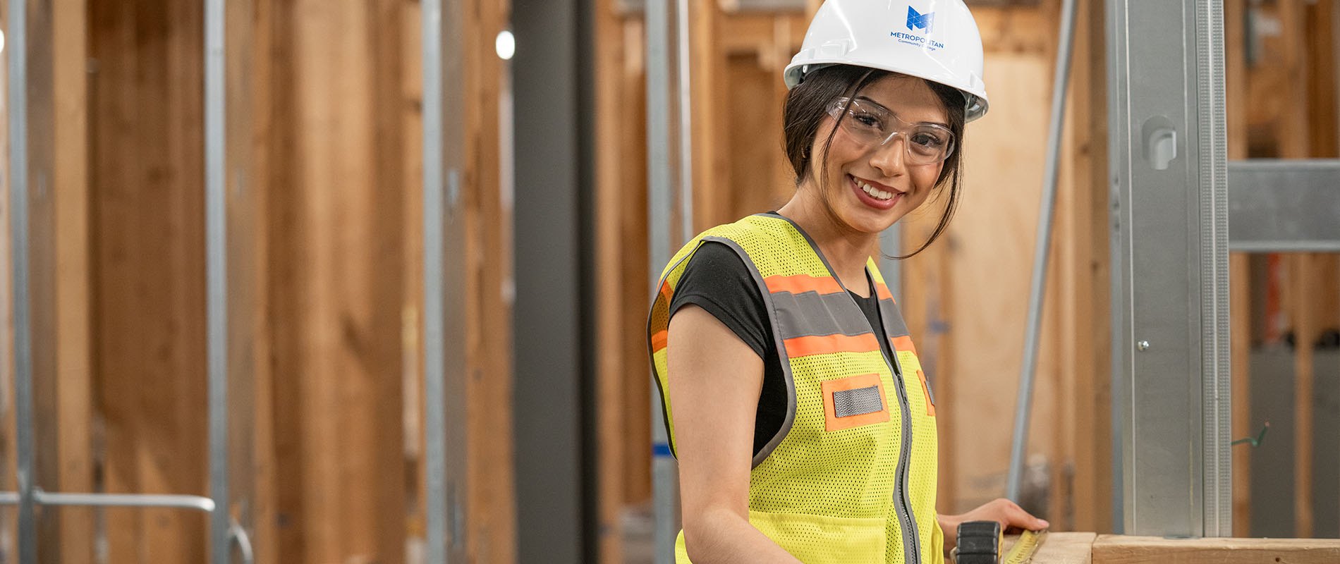 Student wearing hard hat and safety glasses measuring plywood