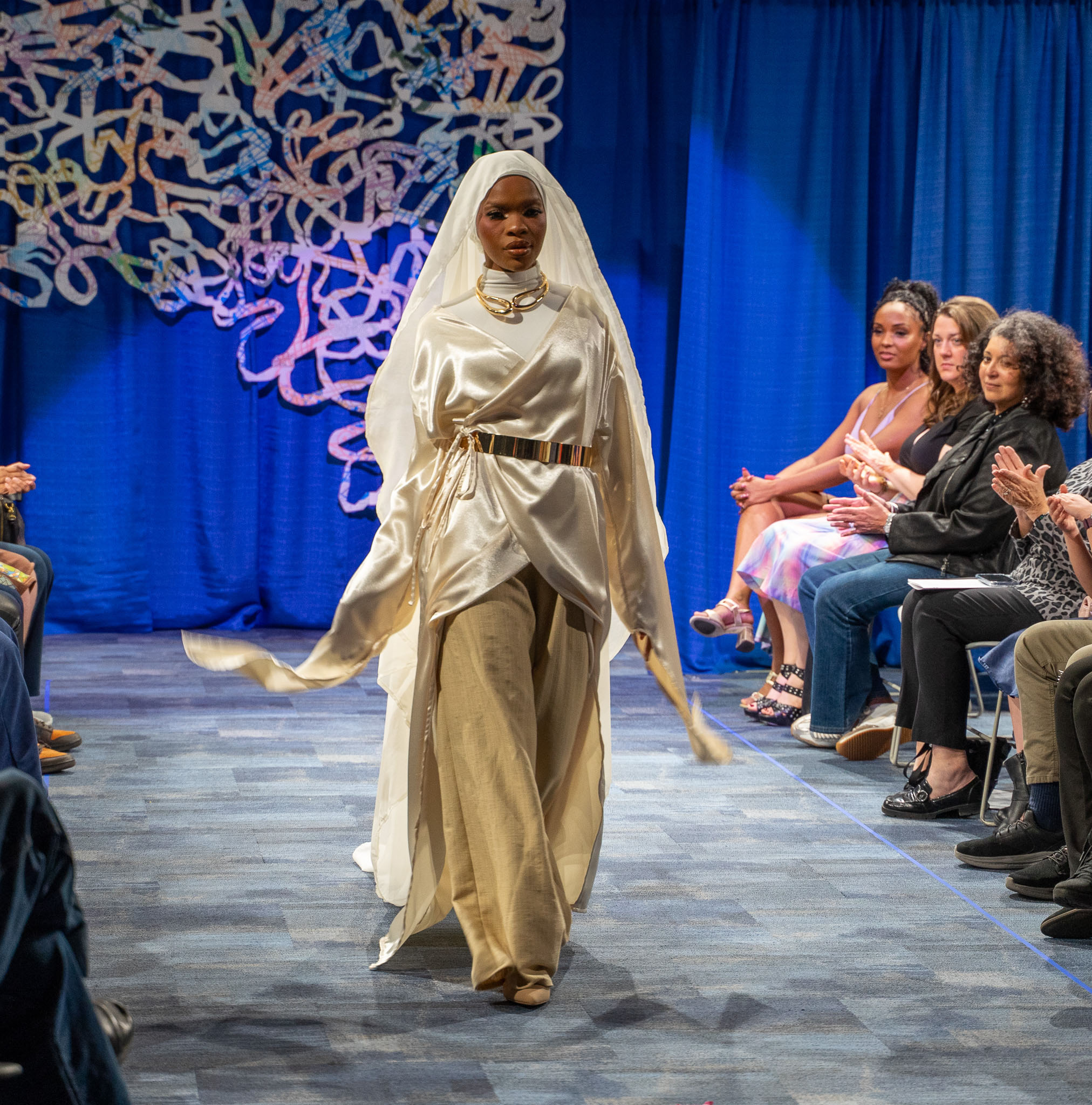 Student model in white dress walking down runway