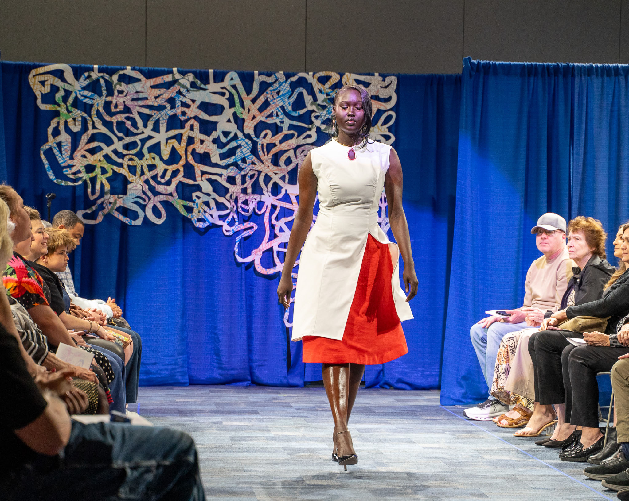 Student model in red and white walking down runway