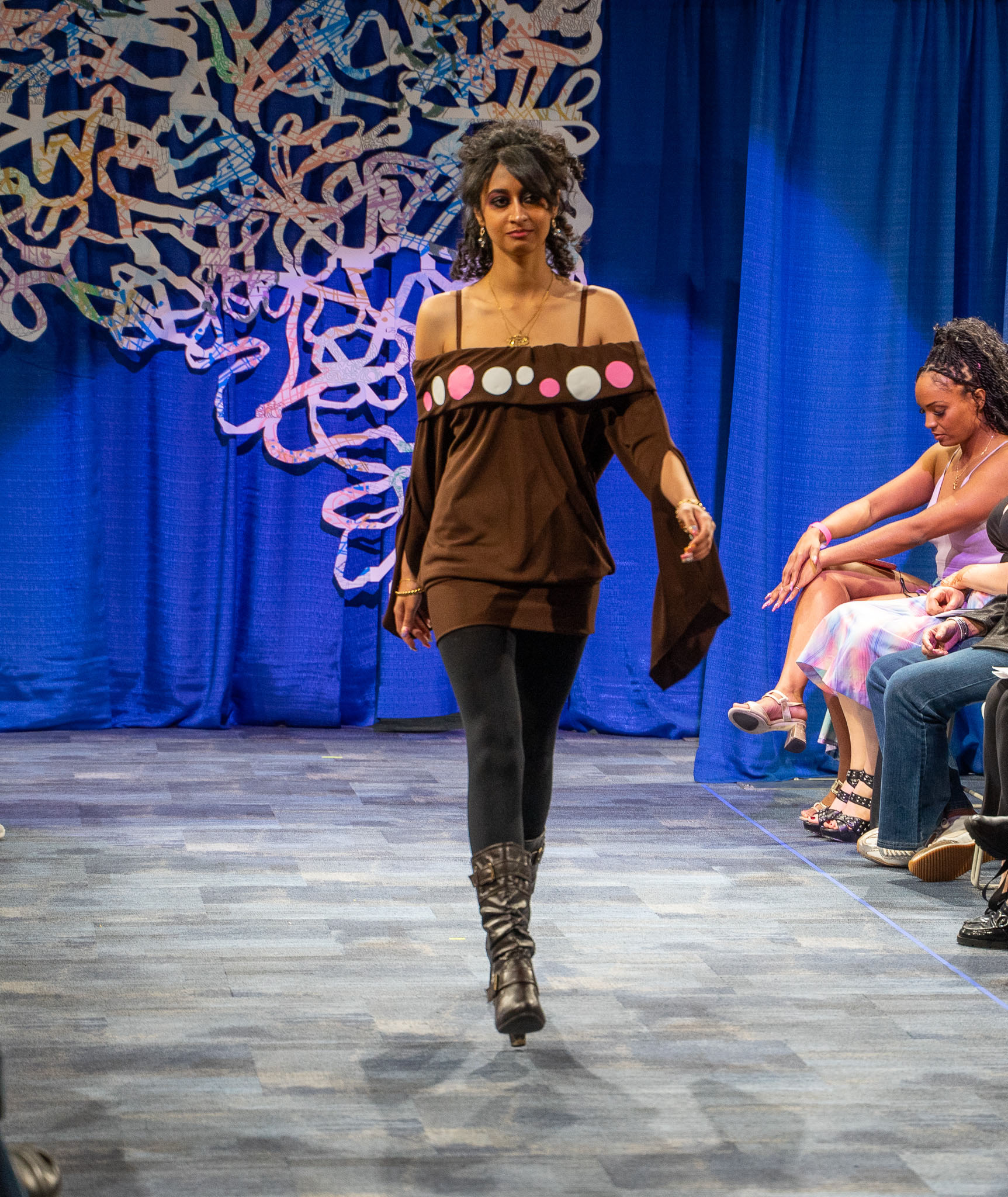 Student model in brown dress walking down runway