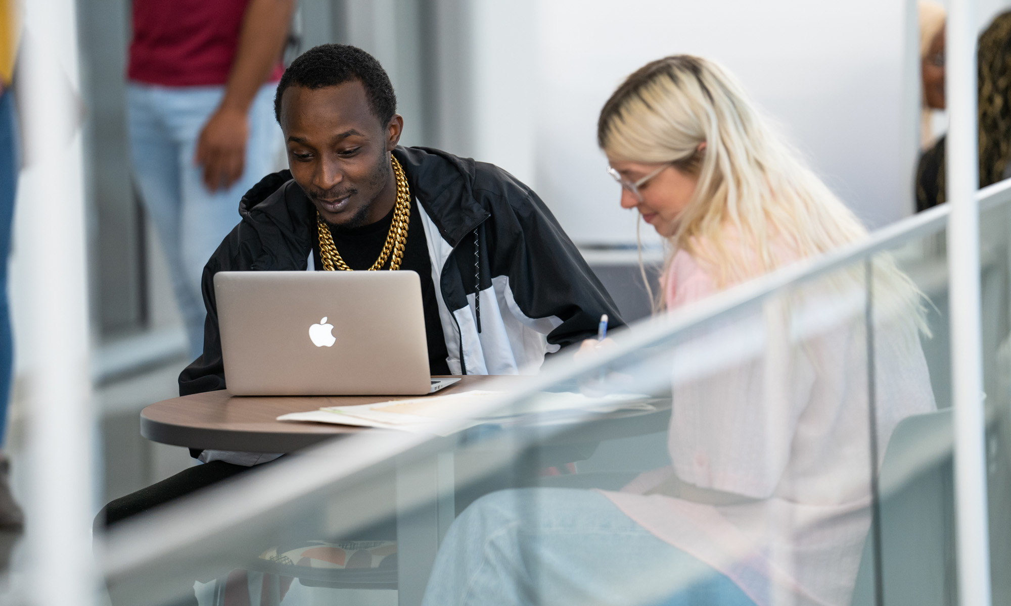 Two students working on laptops at table